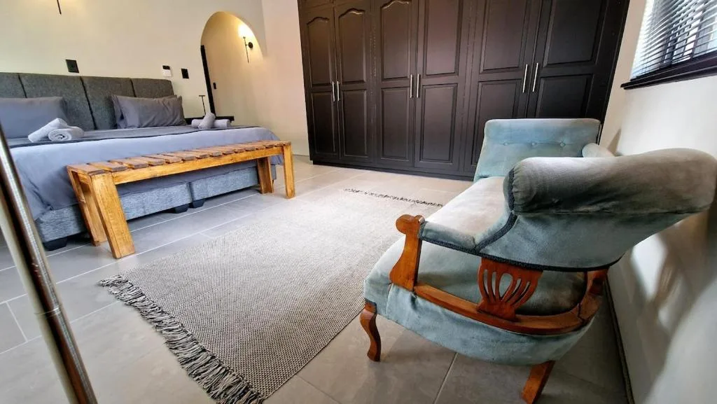 Spacious bedroom with king bed, armchair, and dark wooden wardrobe