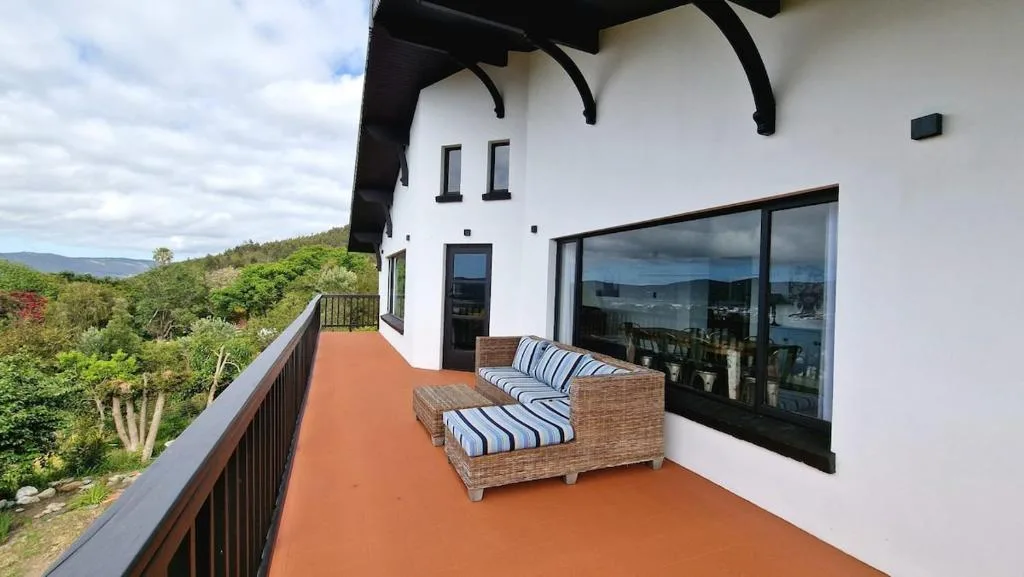 Spacious terracotta deck with wicker seating overlooking lush valley landscape