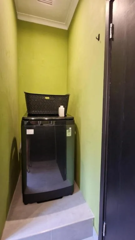 Black washing machine in bright yellow utility room with laundry basket
