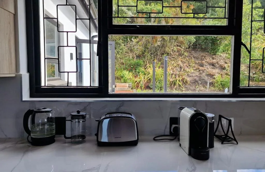Kitchen counter with kettle, toaster, coffee maker, and garden views