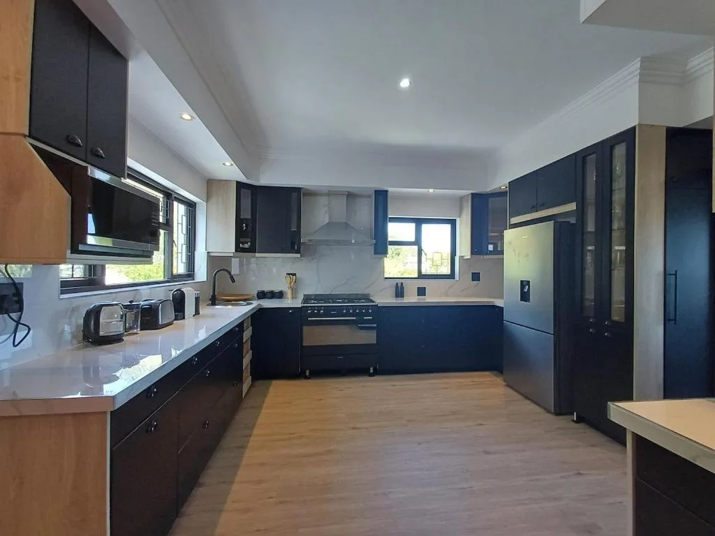 Modern kitchen with dark cabinetry, stainless steel appliances, and white countertops