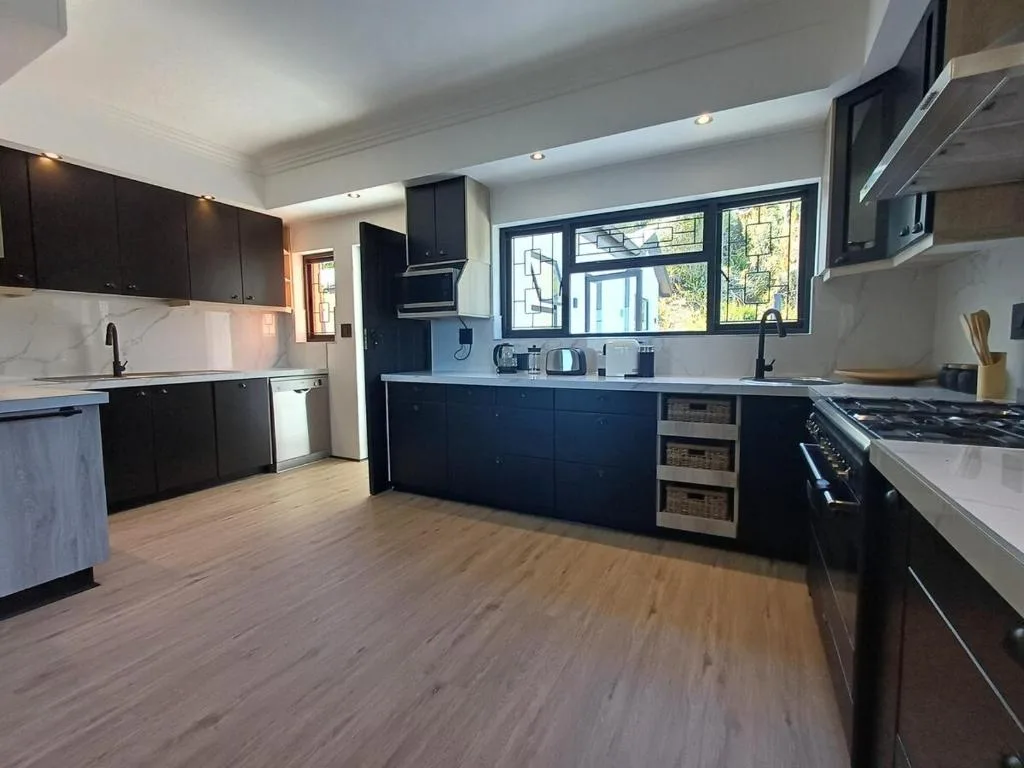 Modern kitchen with dark cabinetry, gas stove, and garden views through windows