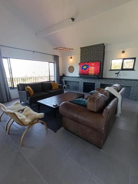 Spacious lounge with brown leather seating and fireplace, large windows overlooking the lagoon