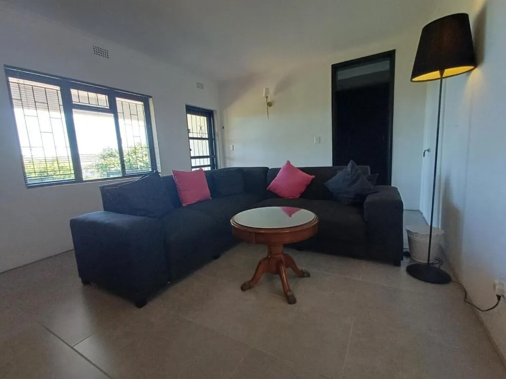 Spacious living room with dark sectional sofa and colorful cushions