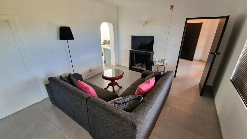Modern living room with gray sofa, pink pillows, fireplace, and flat-screen TV