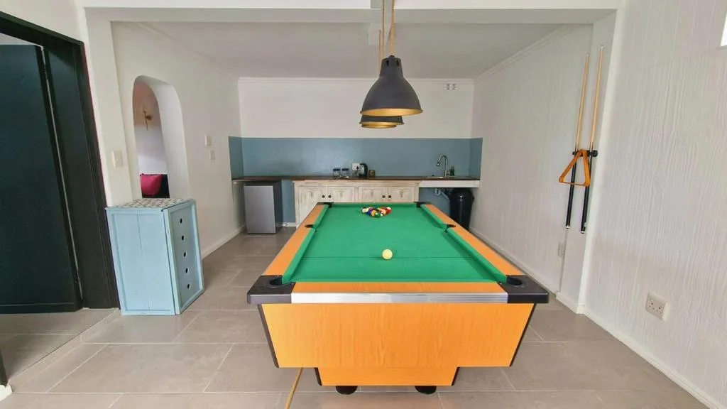 Game room with pool table, pendant lighting, and kitchenette in background