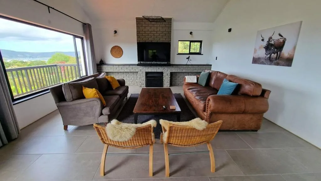 Spacious living room with leather sofas, fireplace, and scenic lagoon views