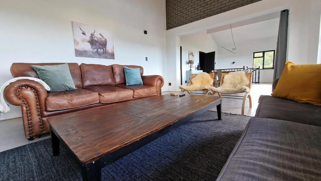 Open-plan lounge with cognac leather sofa, wooden coffee table, and colorful accent pillows