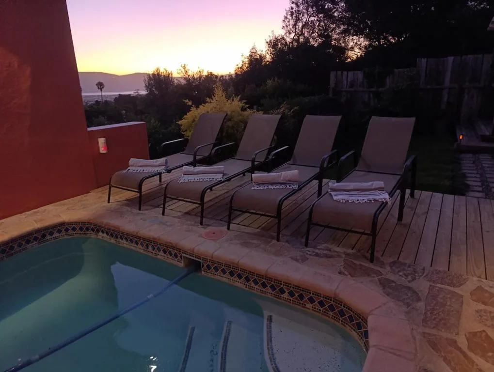 Swimming pool at sunset with lounge chairs and mountain views beyond