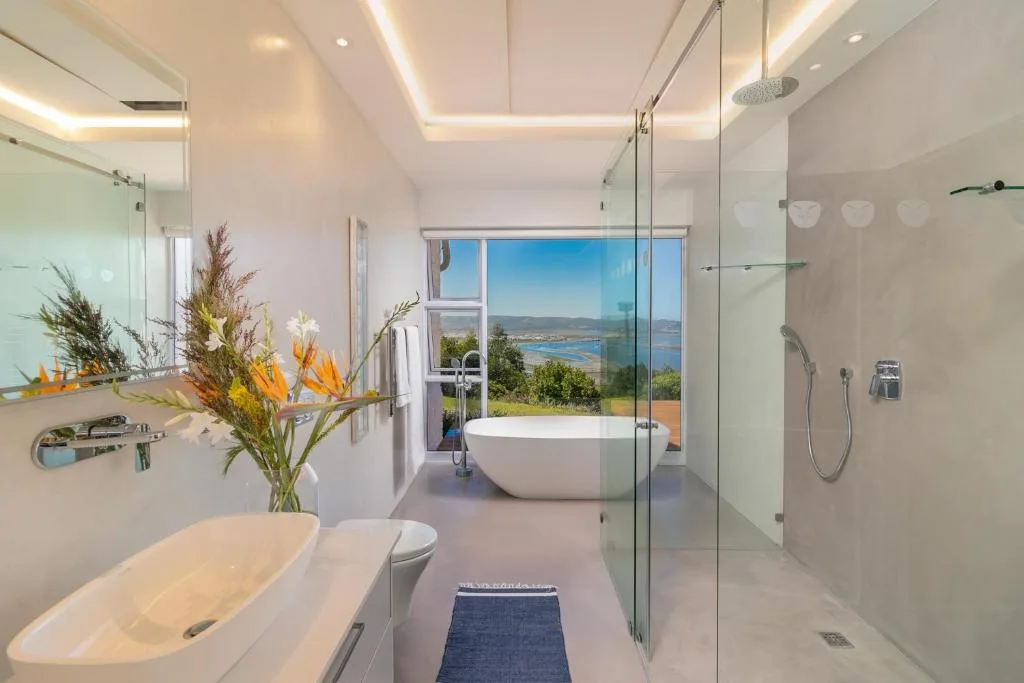 Modern bathroom with dual vanity, freestanding tub, and ocean view through windows