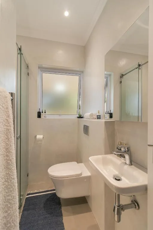 Modern bathroom with toilet, sink, mirror, and glass shower enclosure