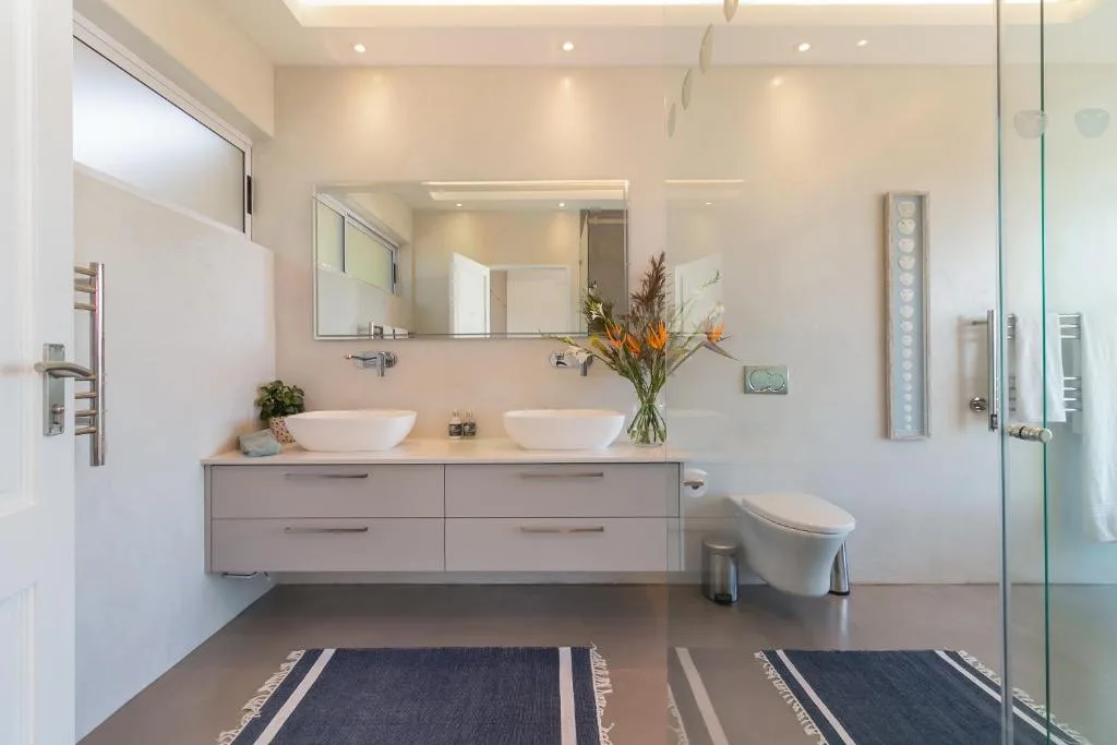Modern bathroom with dual vanity sinks, large mirror, and glass shower enclosure