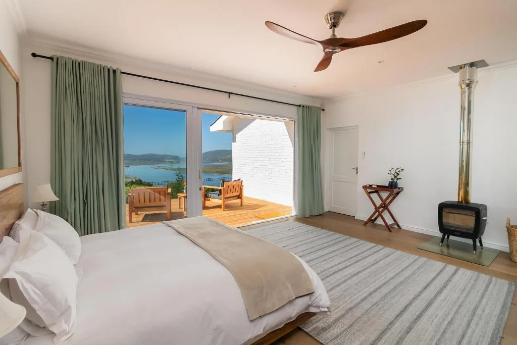 Modern bedroom with king bed, ceiling fan, and lagoon views through glass doors