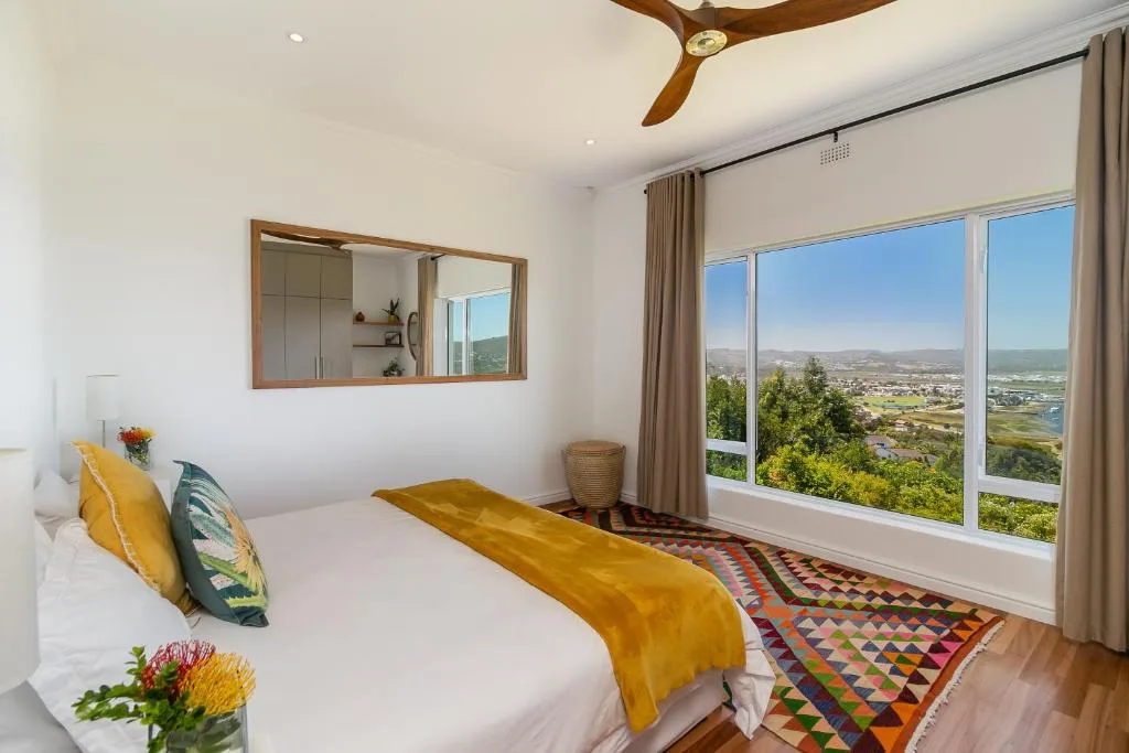 Bright bedroom with valley views, wooden ceiling fan, and colorful accents
