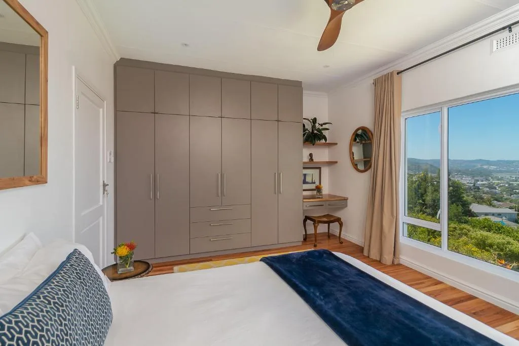 Bright bedroom with large built-in wardrobe and panoramic valley views through windows