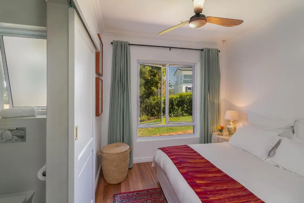 Bright bedroom with double bed, garden views, and ceiling fan