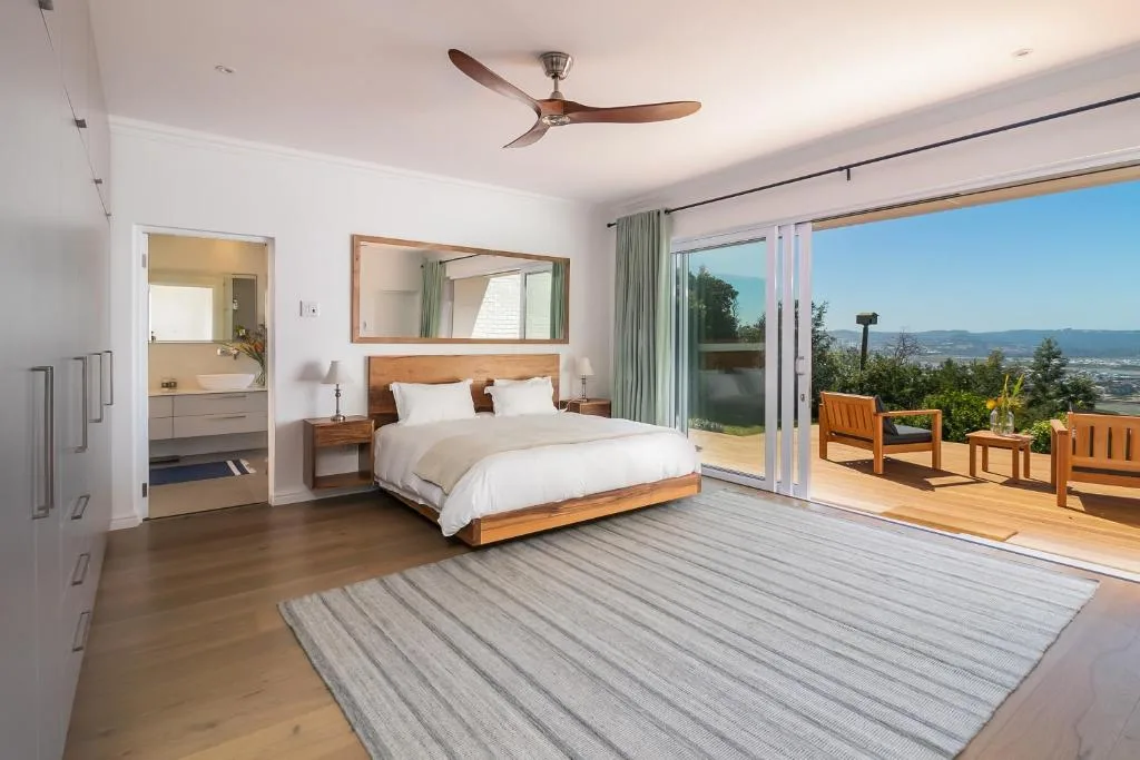 Spacious master bedroom with wooden bed, ensuite bathroom, and valley views