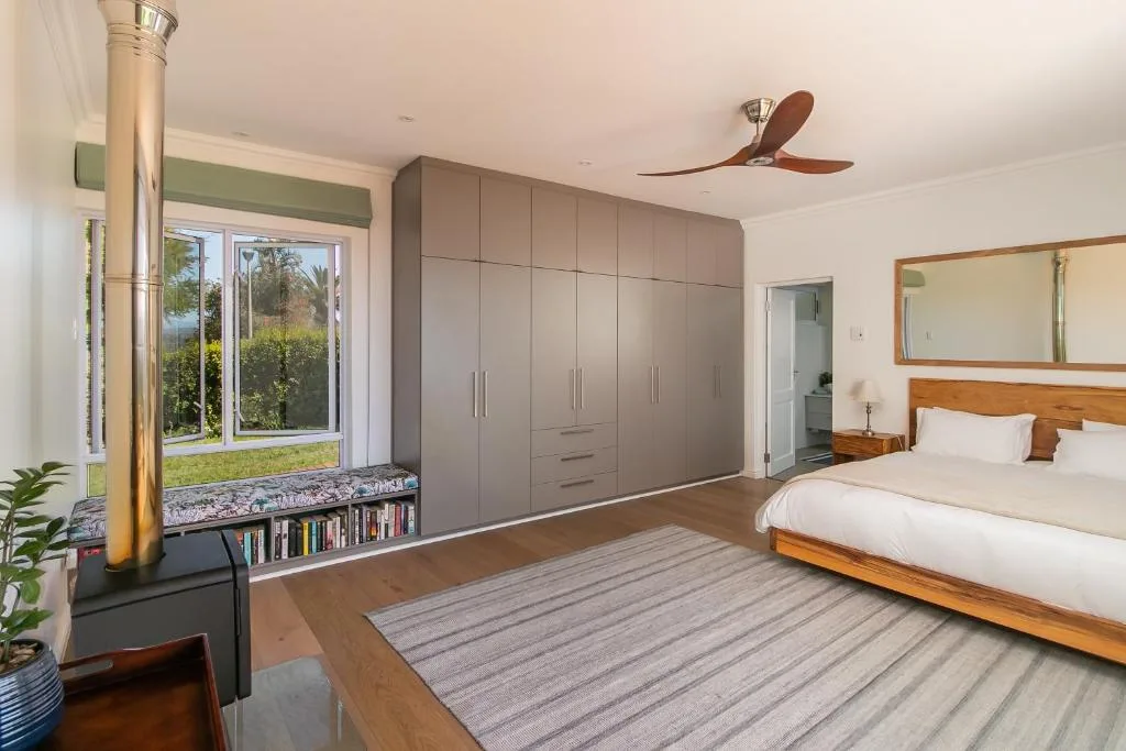 Spacious bedroom with wooden bed, large wardrobe, and garden views