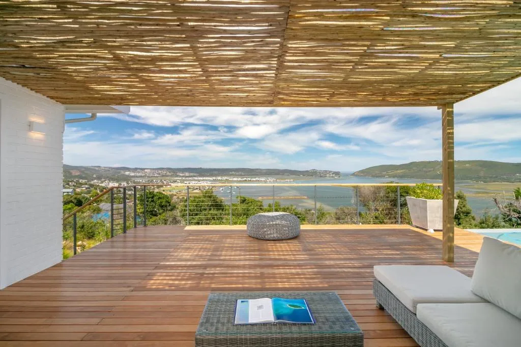 Spacious wooden deck with pergola, outdoor seating, and panoramic lagoon views