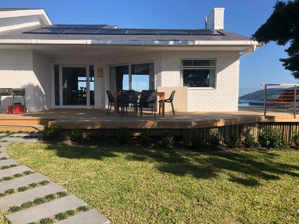 Modern white brick home with wooden deck and garden overlooking water