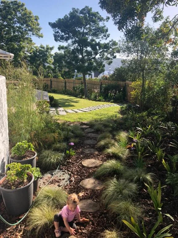 Landscaped garden with native plants, stepping stones, and lush green lawn