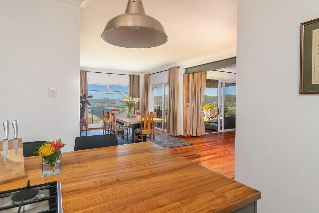 Modern kitchen with wood counters opening to dining and lounge areas with sea views