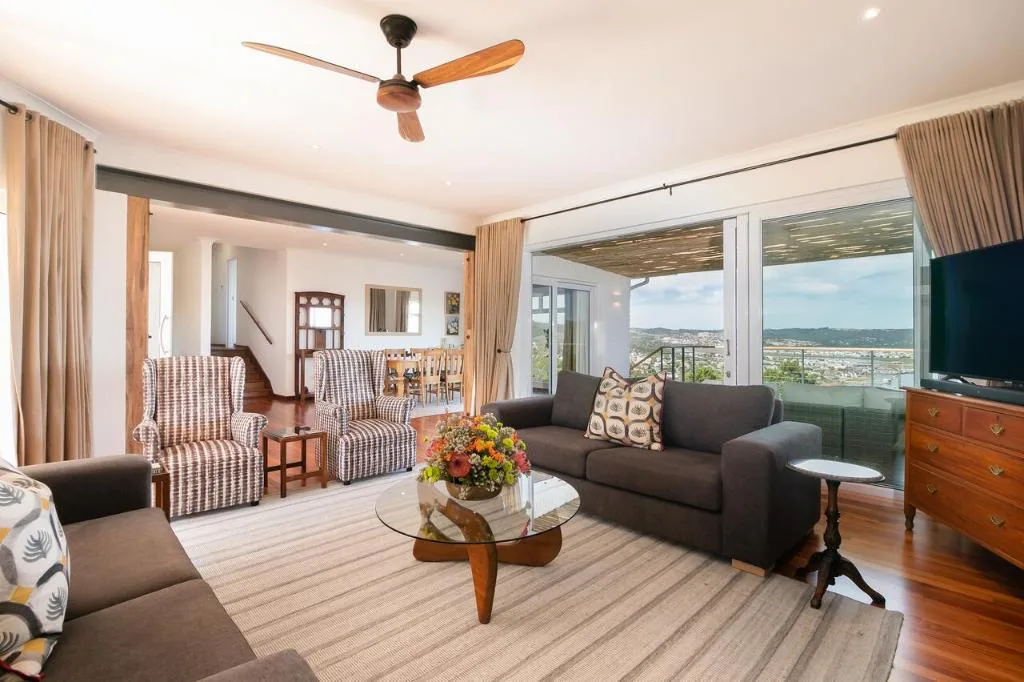 Spacious lounge with sofa, armchairs, and panoramic valley views through large windows