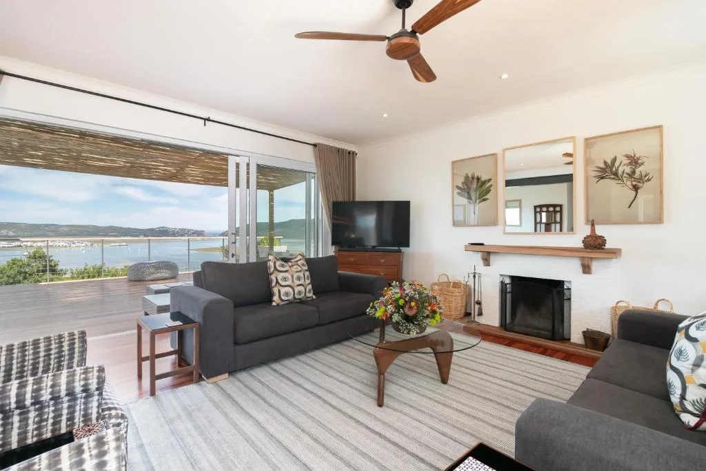 Modern lounge with black sofa, fireplace, and expansive lagoon views through glass doors