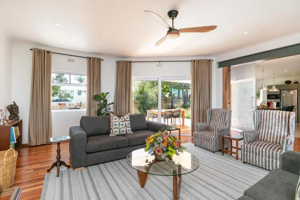 Spacious open-plan lounge with gray sofa, patterned armchairs, and garden views