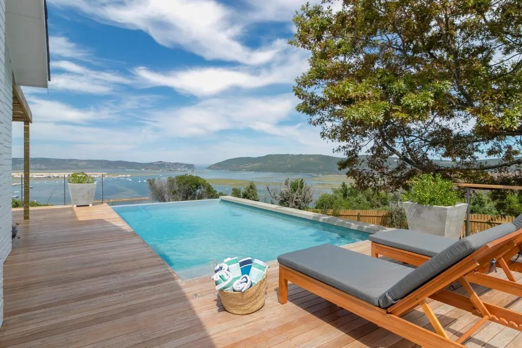 Swimming pool with wooden loungers overlooking Knysna lagoon and mountains