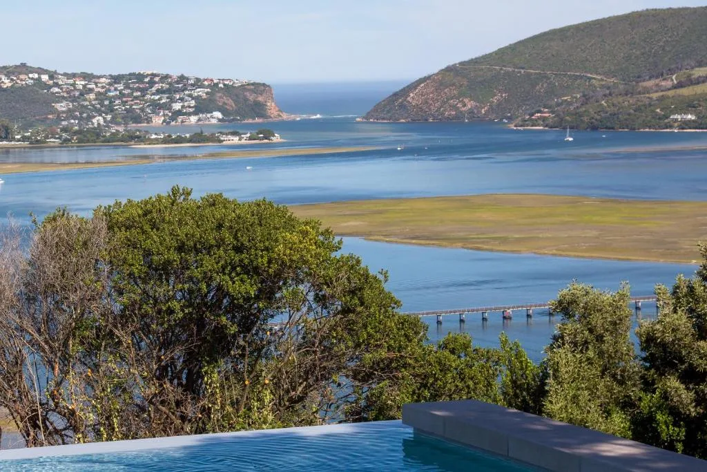 Stunning lagoon and ocean vista with forested hills and coastal town beyond