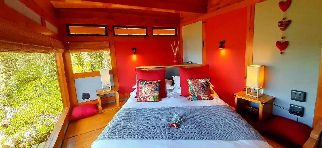 Bright red bedroom with double bed, wooden furniture, and garden views