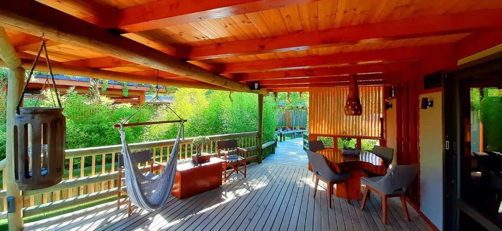 Covered wooden deck with hammock, seating, and vibrant red-orange beams