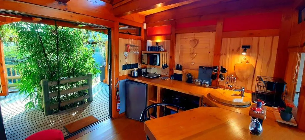 Warm wooden lounge with desk area, opening onto garden deck with water view
