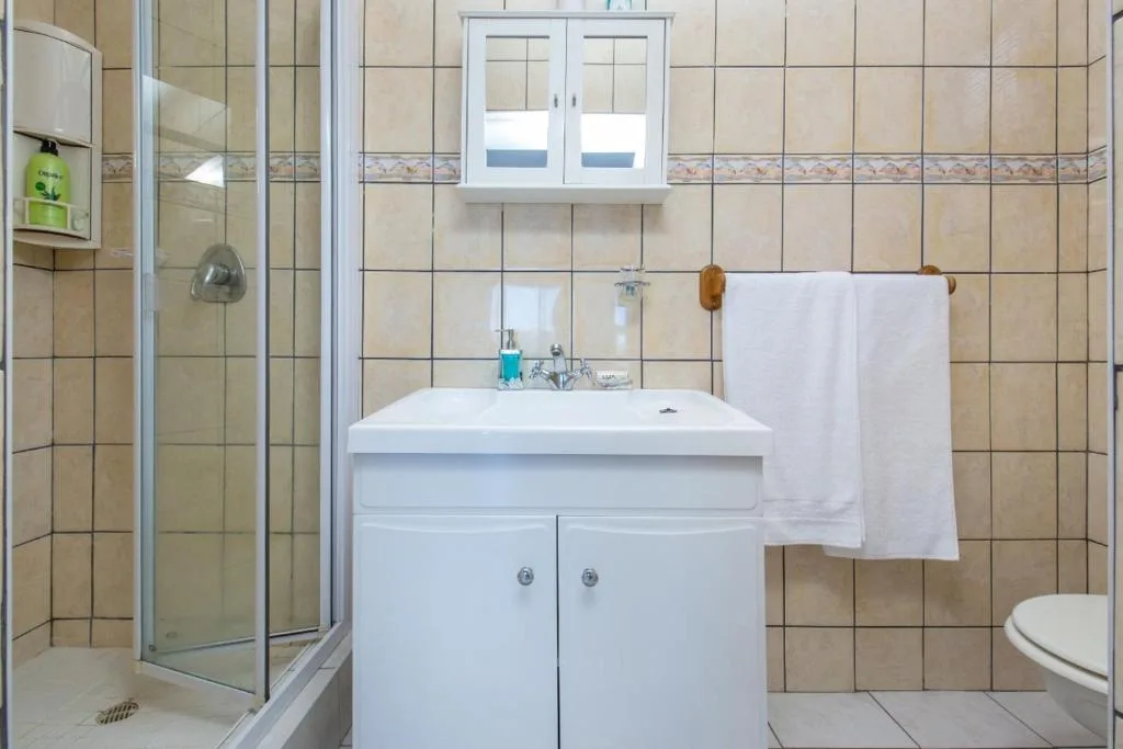Bathroom with white vanity, shower cubicle, and beige tile walls