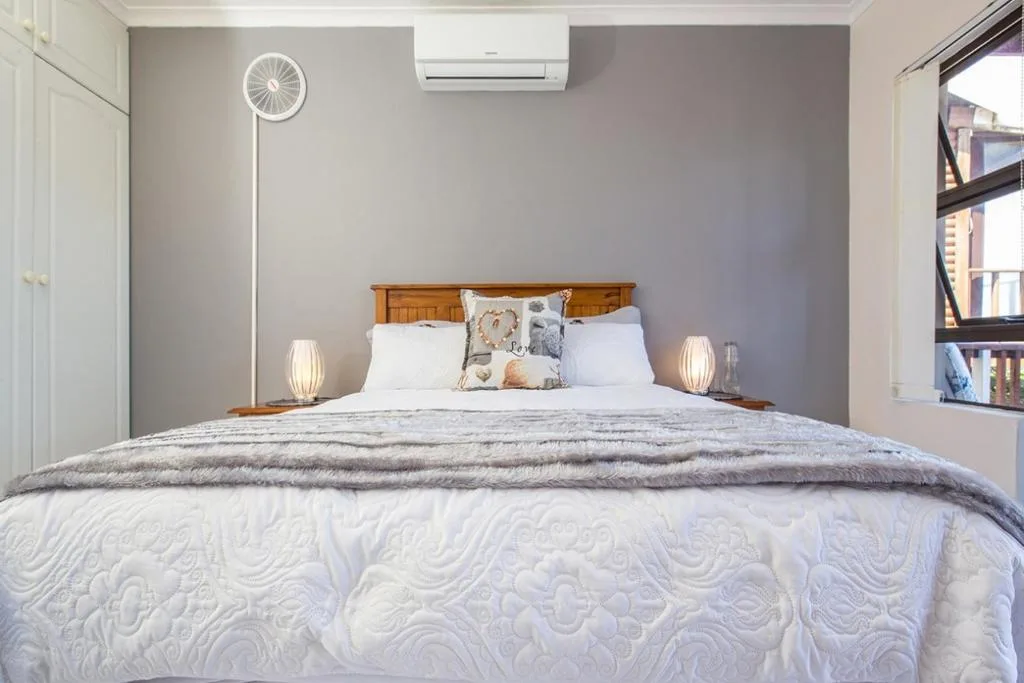 Modern bedroom with wooden headboard, white bedding, and accent pillows