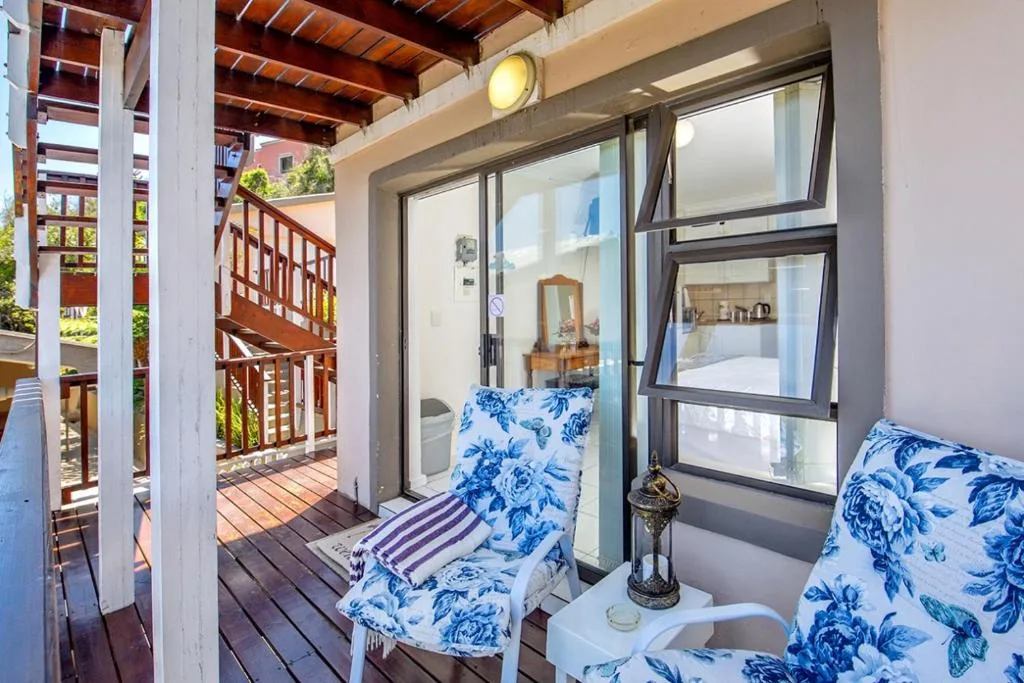 Wooden deck with blue patterned cushioned seating and garden views
