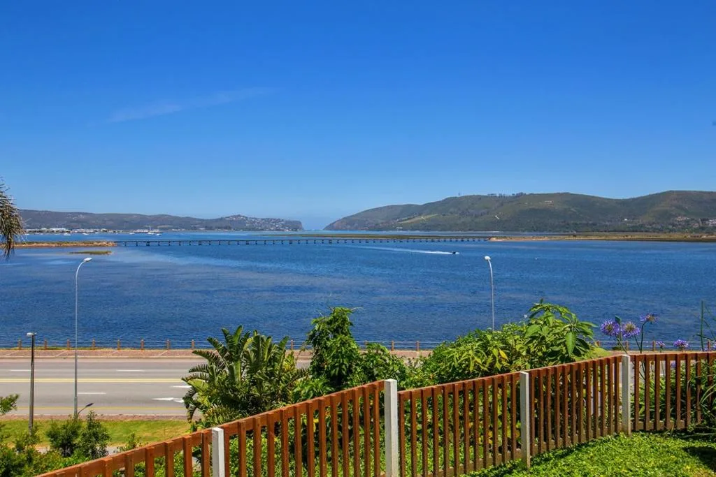 Scenic lagoon view with bridge, mountains, and blue water from deck