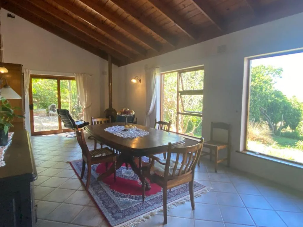 Dining area with wooden table, chairs, and garden views through large windows