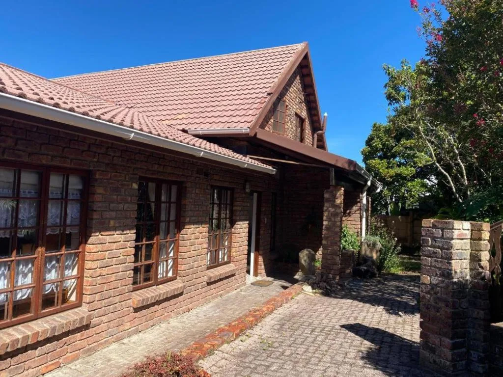 Brick cottage exterior with tiled roof and lush garden surroundings