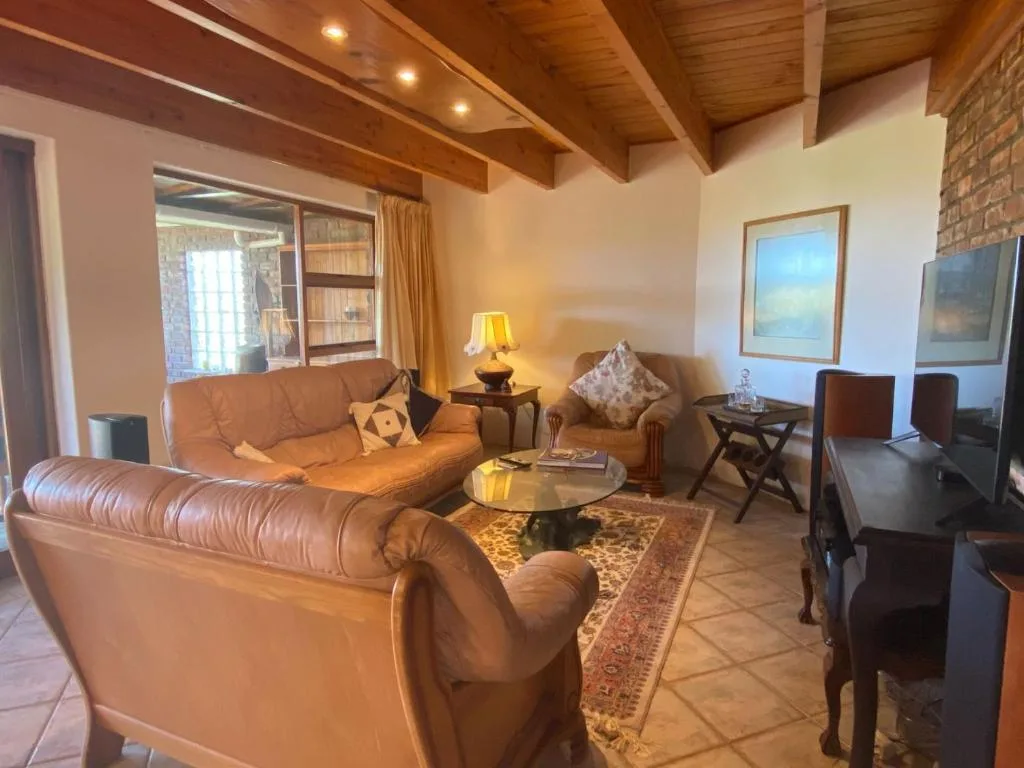 Spacious lounge with leather sofas, wooden beams, and warm lighting