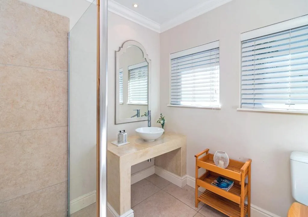 Modern bathroom with vanity sink, mirror, shower enclosure, and wooden shelving