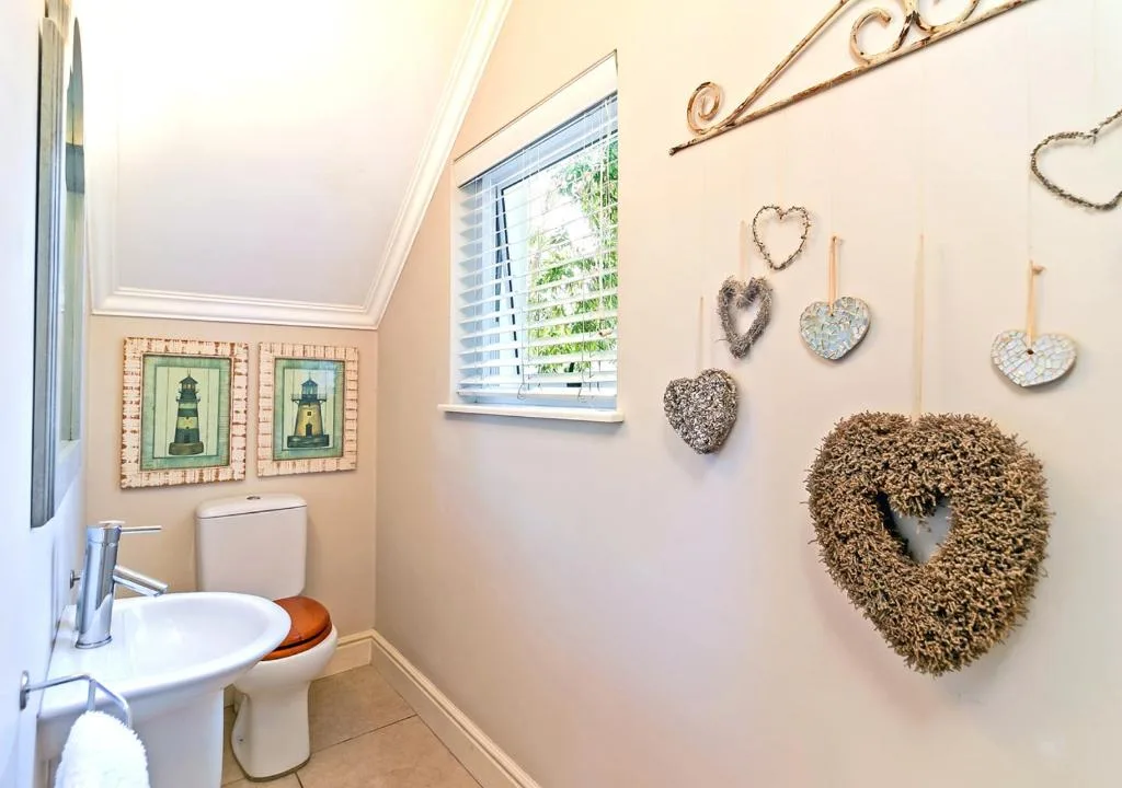 Bathroom with toilet, sink, window, and decorative heart-shaped wall ornaments