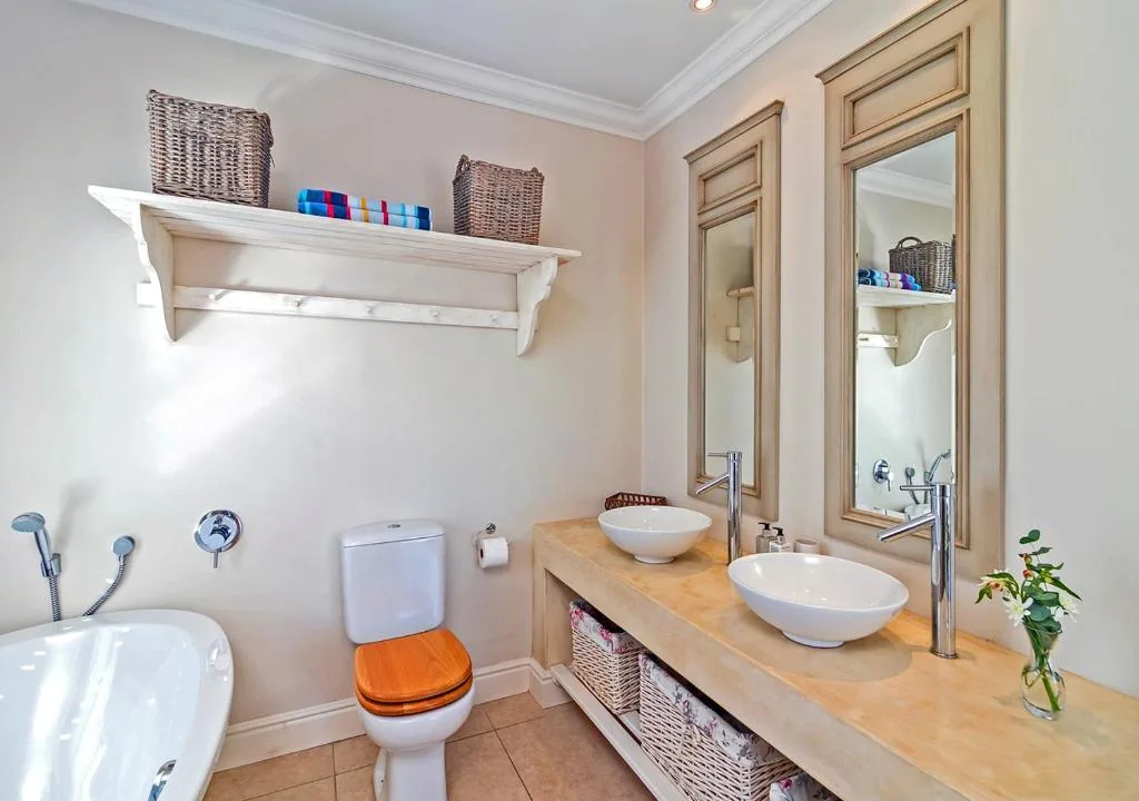 Spacious bathroom with dual vessel sinks, wooden vanity, and storage baskets