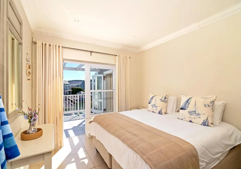 Bright bedroom with queen bed, nautical cushions, and deck access