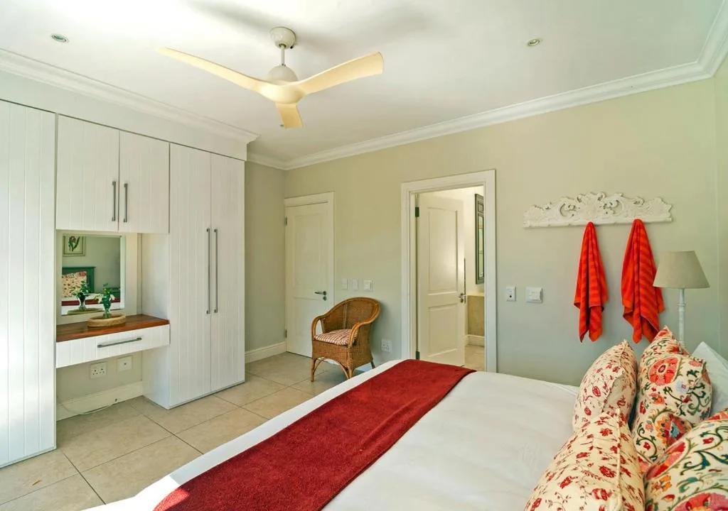 Spacious bedroom with white cabinetry, colorful pillows, and ensuite bathroom