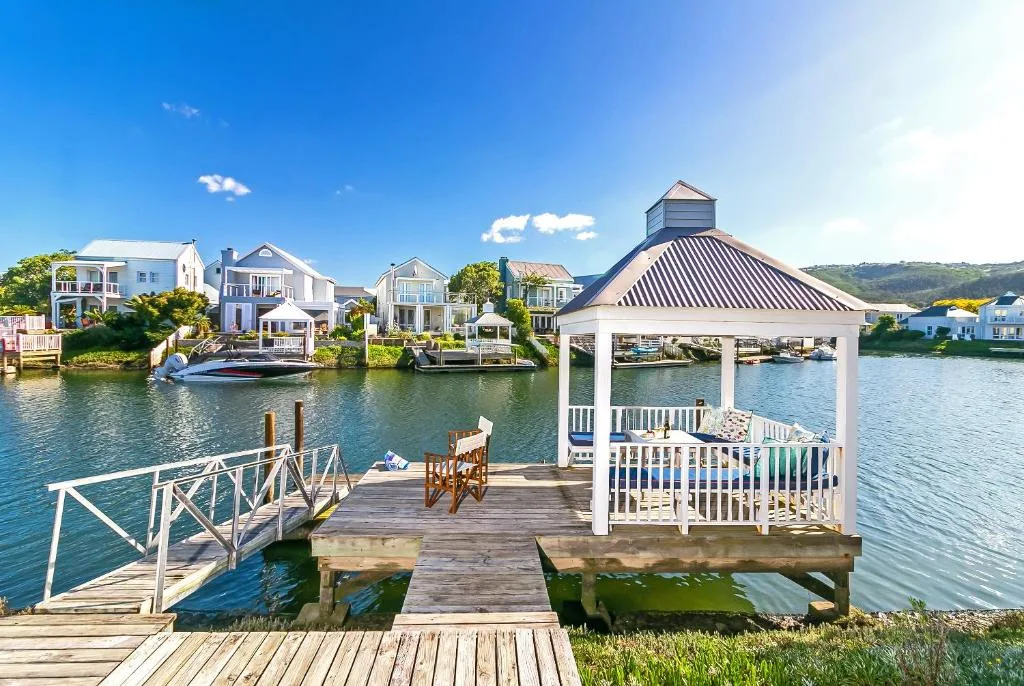 Waterfront deck with white gazebo and wooden chairs overlooking canal