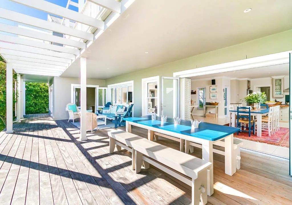 Spacious covered deck with dining table and comfortable seating areas overlooking garden