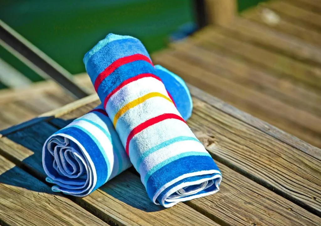 Colorful striped beach towels rolled on wooden deck
