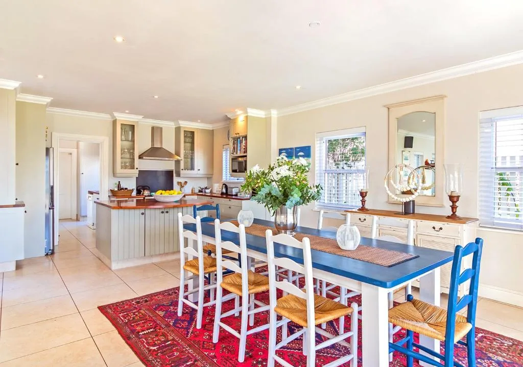Open-plan dining and kitchen with blue-topped table and white chairs